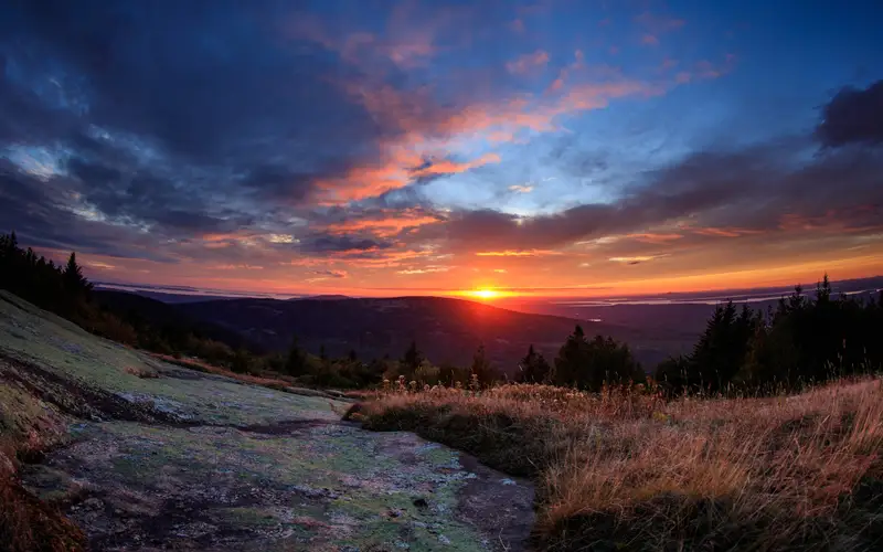 A brilliant sunset filled with hues of blue, red, orange, magenta, and purple highlight the sky.