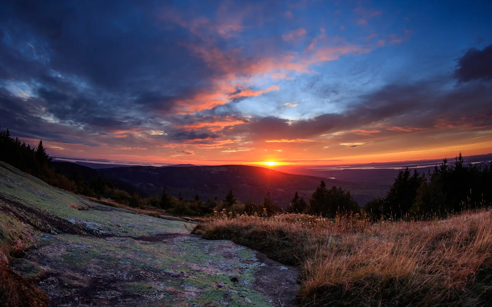 A brilliant sunset filled with hues of blue, red, orange, magenta, and purple highlight the sky.