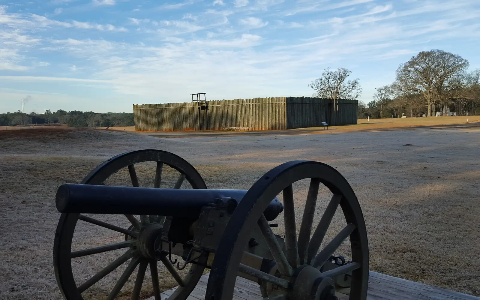 A cannon sits out in front of a replica of part of the wooden stockade walls once at Andersonville