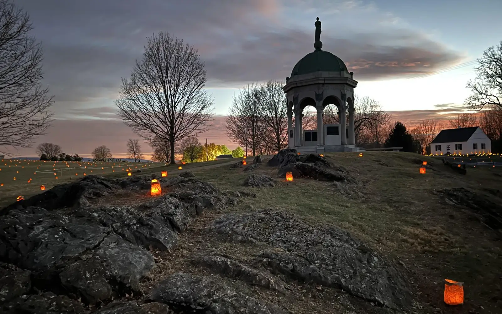 luminaries placed by Maryland Monument with dramatic orange red clouds