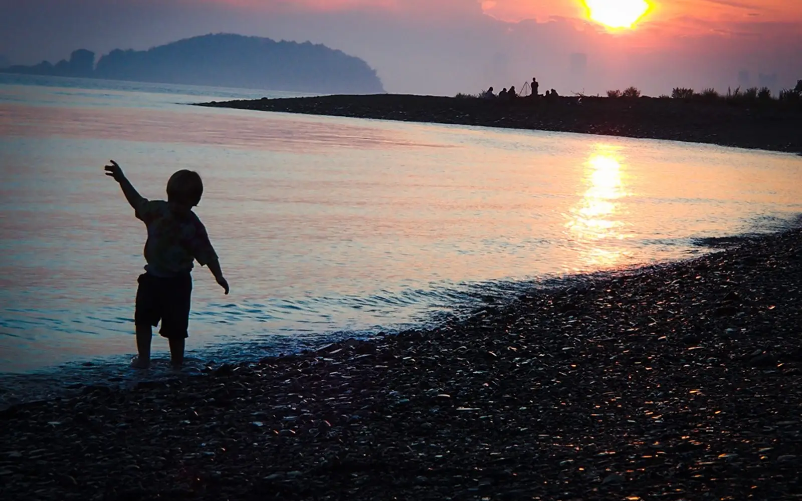 A child dancing on the beach at dusk