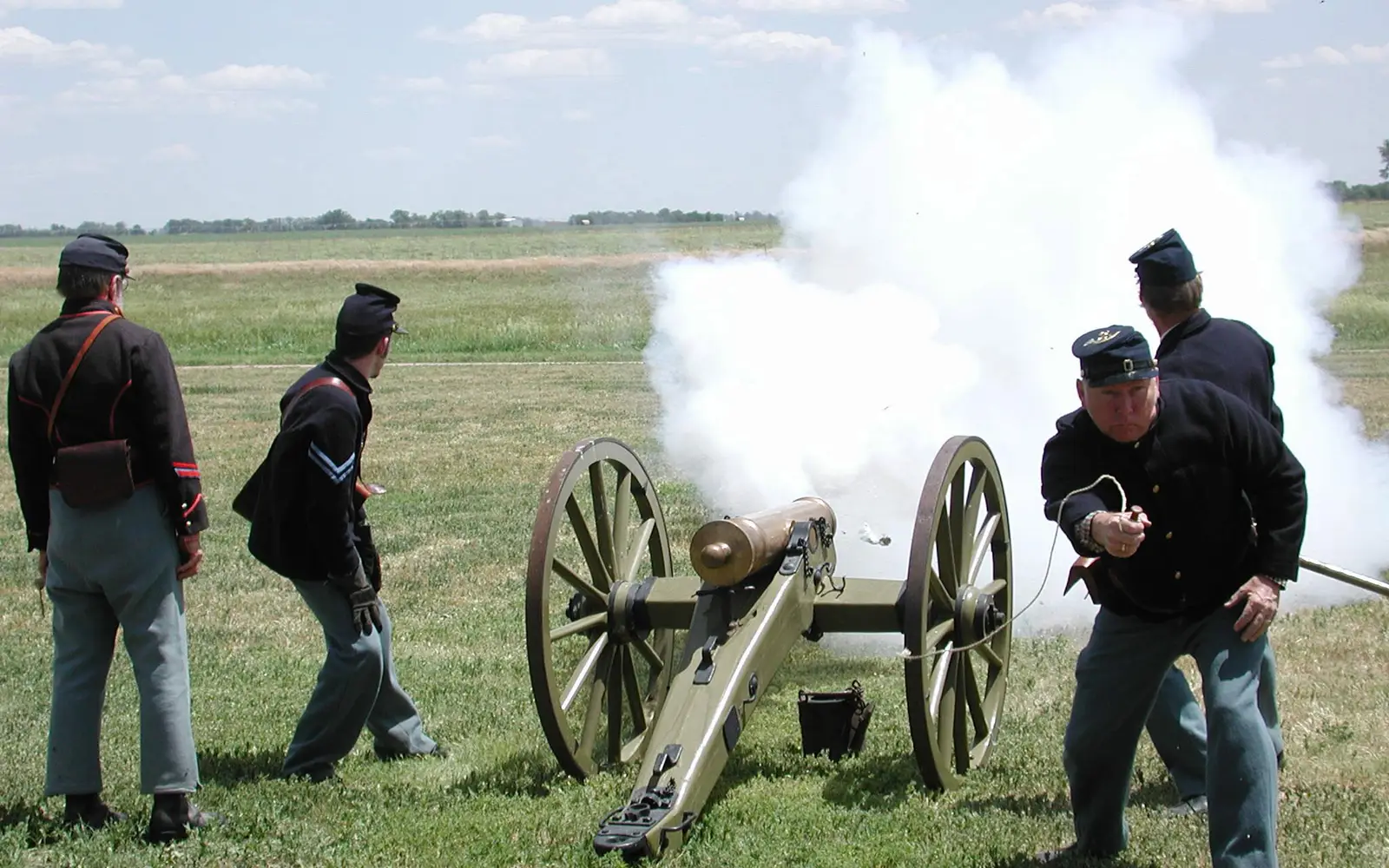 Men in 19th century U.S. Army uniforms fire a reproduction period cannon.