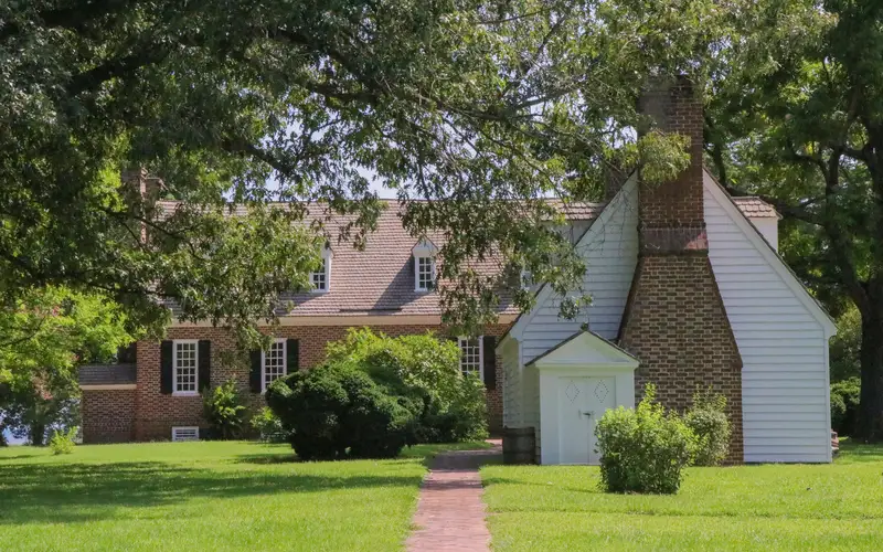 Two buildings surrounded by green foliage with a brick path leading to the buildings.