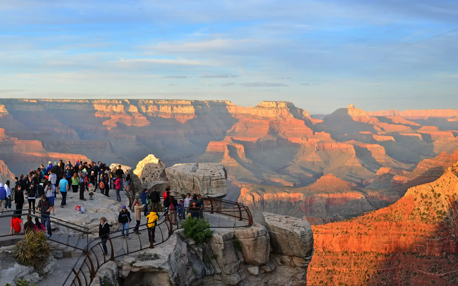 The canyon glows orange as people visit Mather Point, a rock outcropping that juts into Grand Canyon