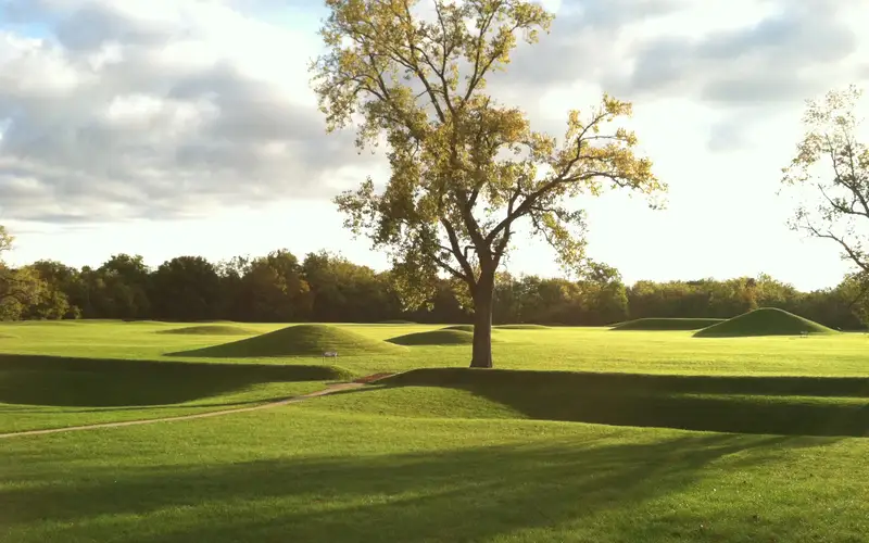 An early morning sun casting long shadows over grass-covered mounds.