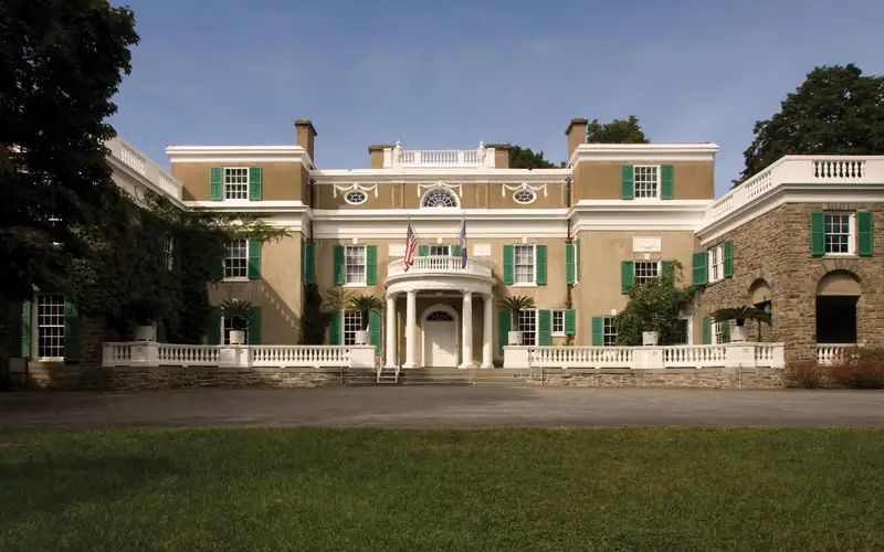 A stucco and fieldstone house with white trim and circular portico.