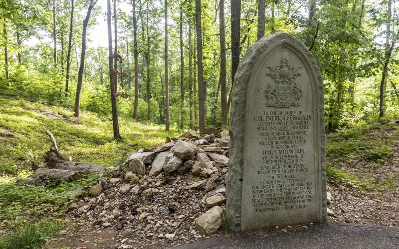An oval gravestone for Maj Patrick Ferguson is in front of his stone covered grave.