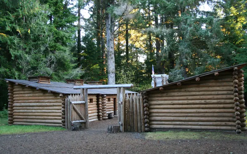 A fifty foot square wooden fort surrounded by tall trees in a forest.