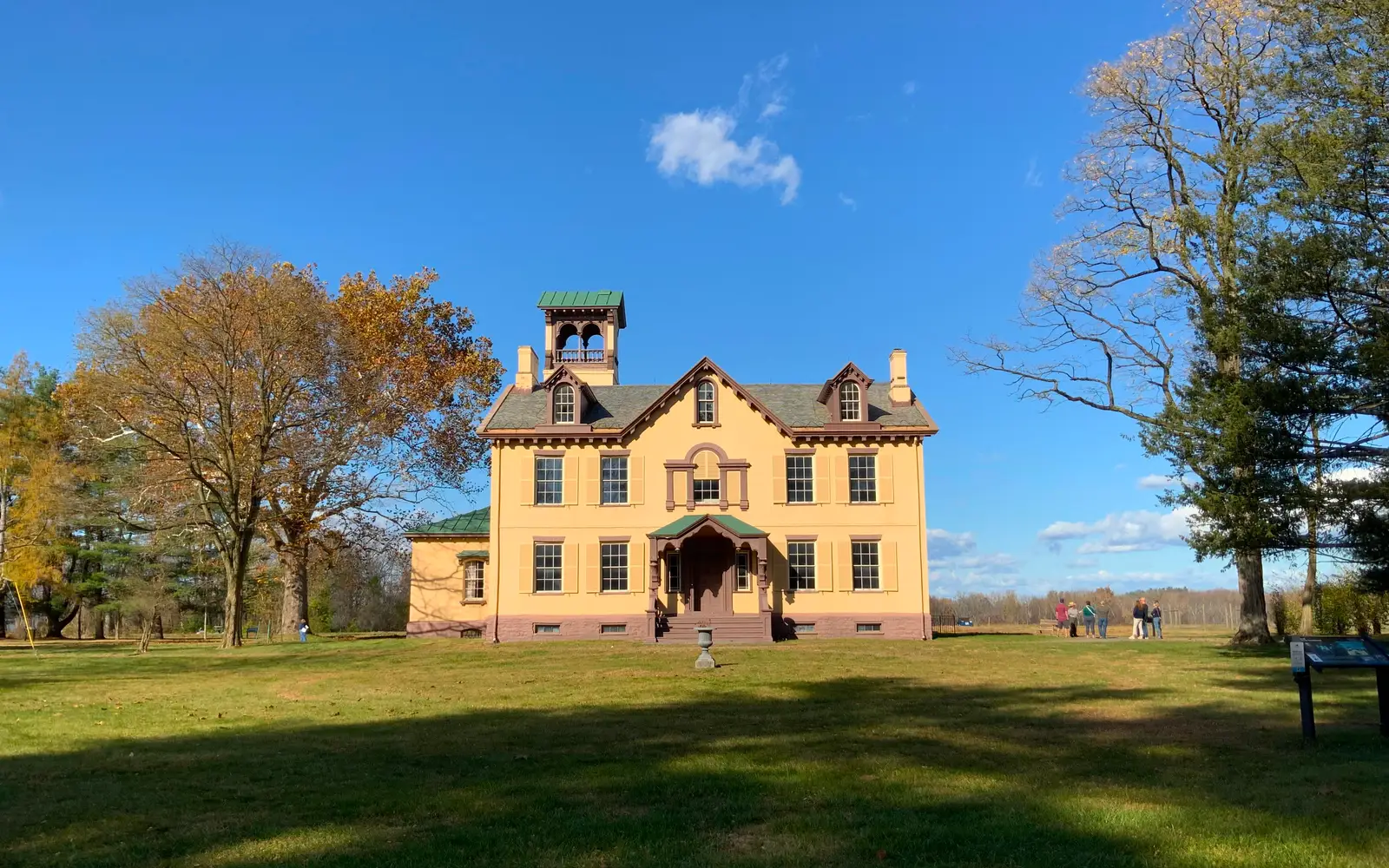 Lindenwald, a yellow, 3 story mansion, is surrounded by trees.