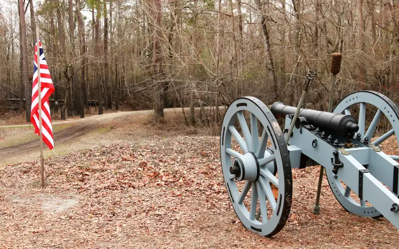 Cannon on a hill on a winter day. American flag to the left of the cannon