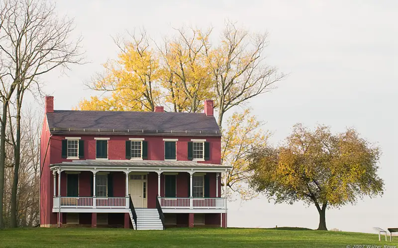 Federal style house with trees behind it during the fall season.