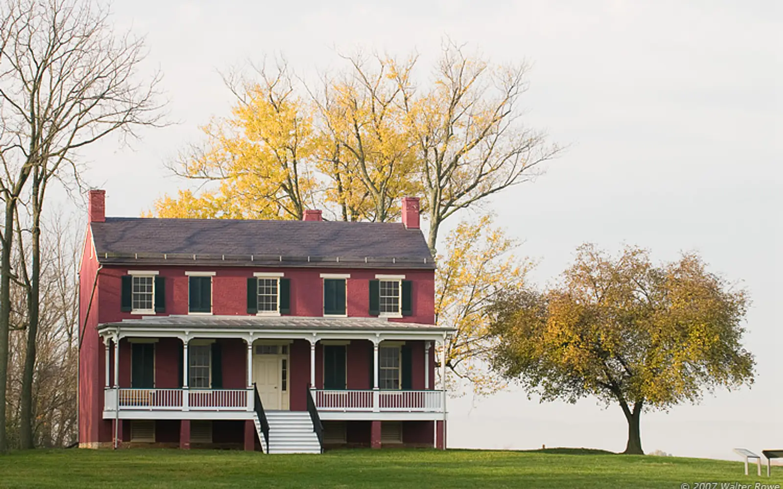 Federal style house with trees behind it during the fall season.