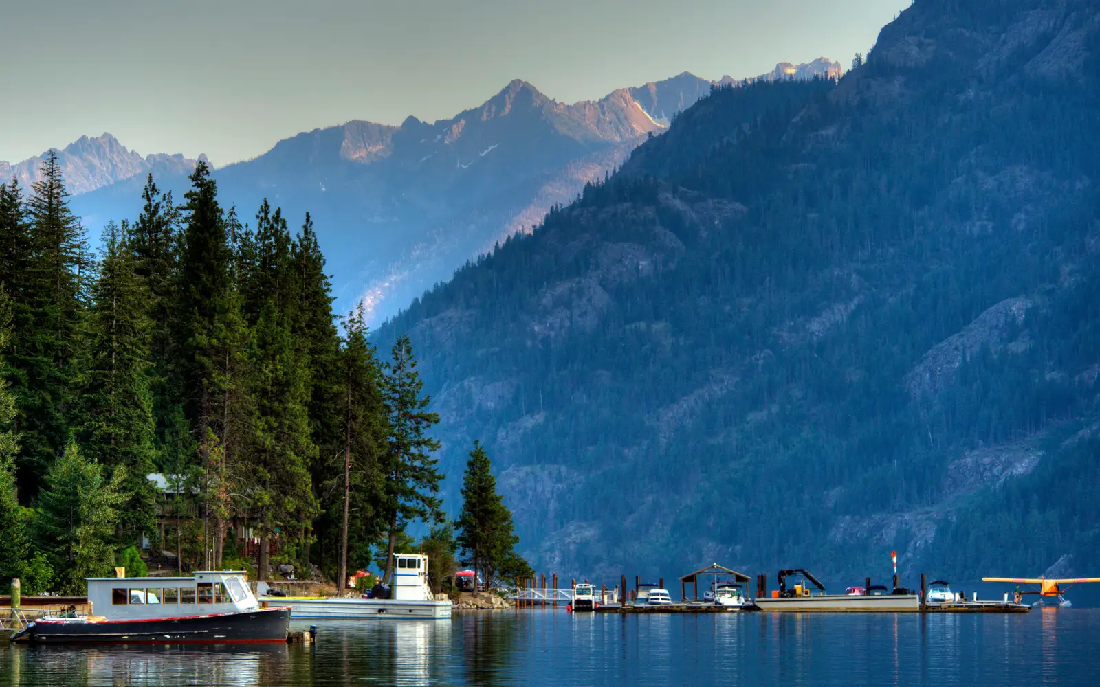 boats on the water with mountains and trees surrounding