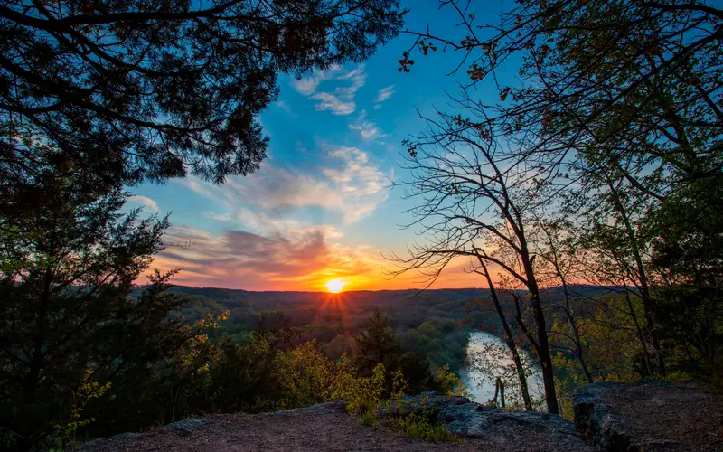 Sunset picture with high vantage point overlooking river with fall colors and sun setting in distanc
