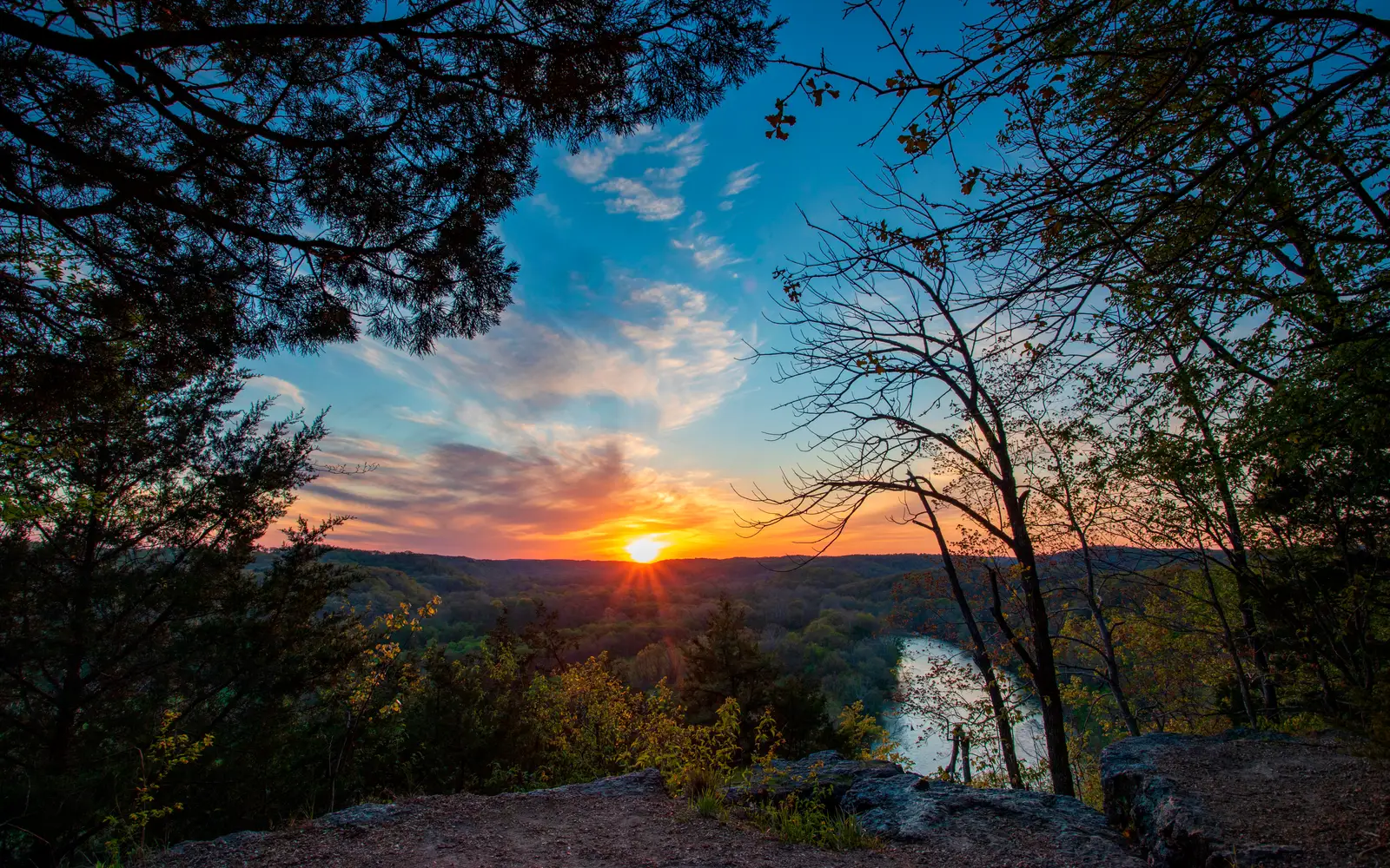 Sunset picture with high vantage point overlooking river with fall colors and sun setting in distanc