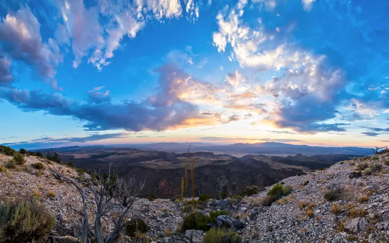 Near a cliff edge the sun sets in the distance.