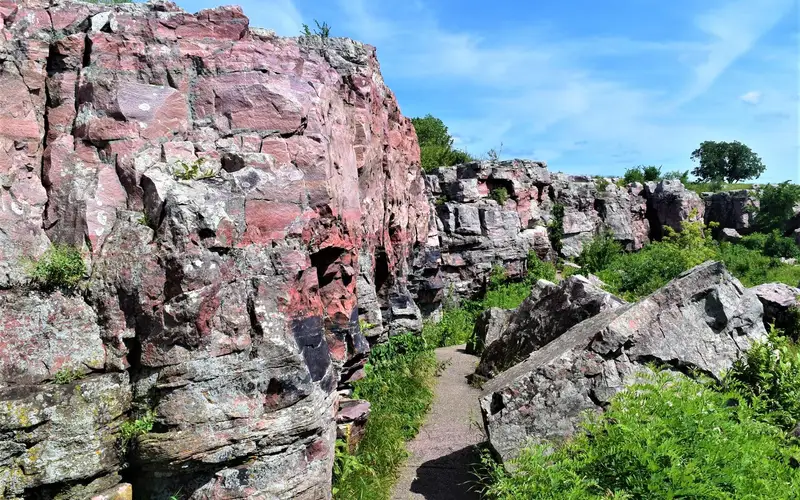 Pink wall of rock next to path and grass