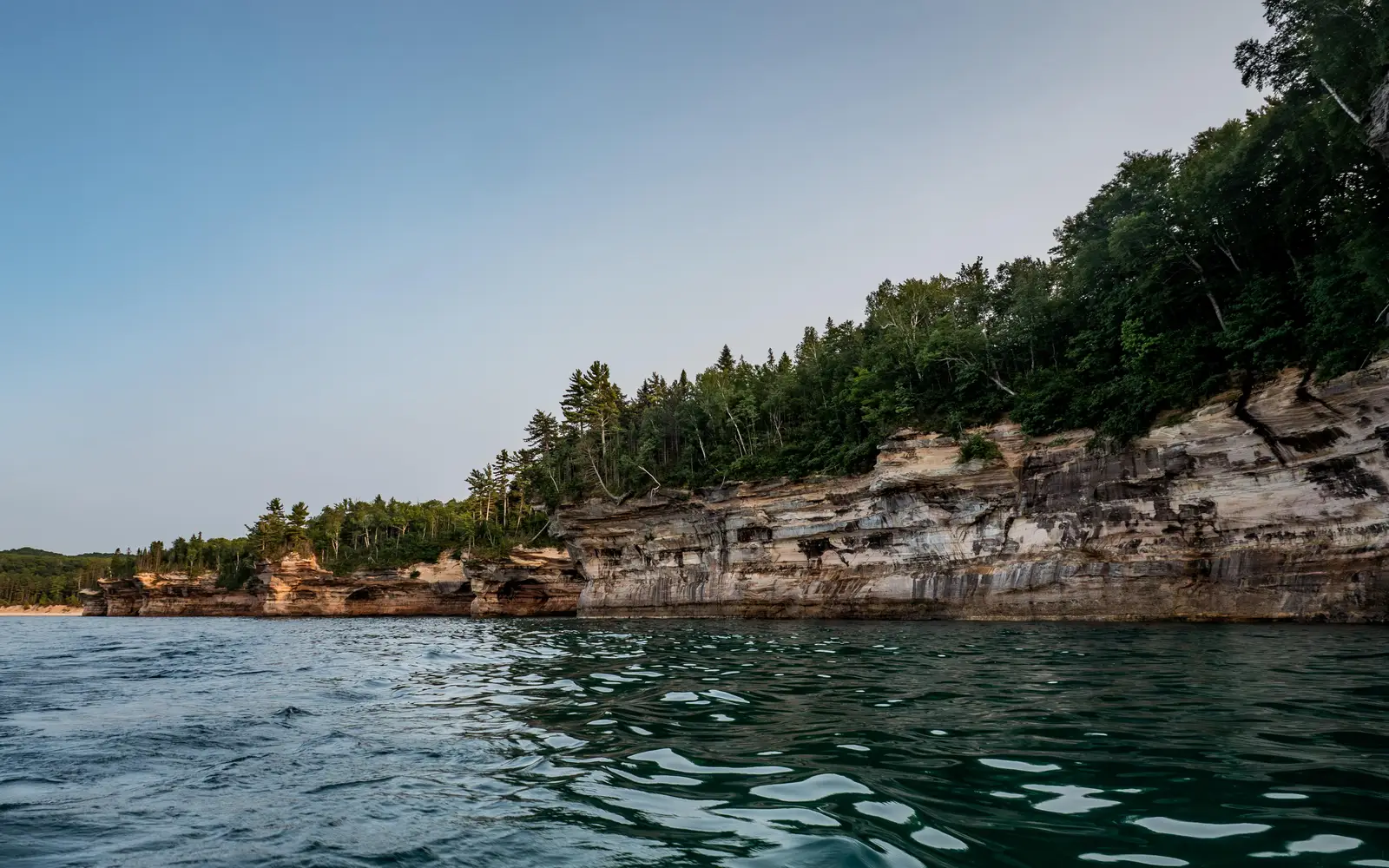 Multi-colored sandstone cliffs rise out of Lake Superior