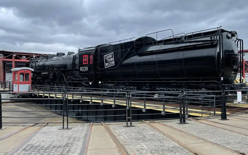 large black train with number 6039 painted in white lettering, sitting on turntable track