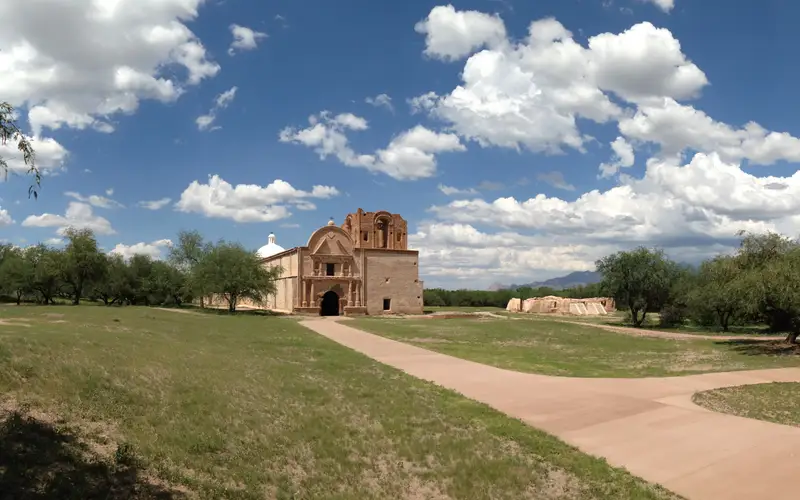 panorama of mission church with green grass and clouds