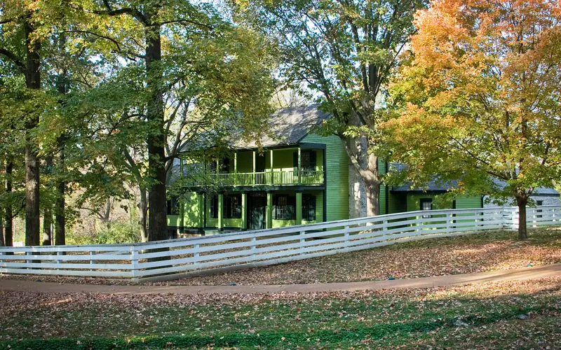 View of house with fence. Autumn colored leaves on trees
