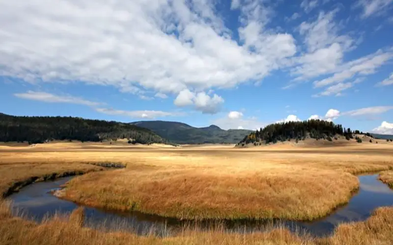Scattered clouds over landscape view of winding river and brown grasslands