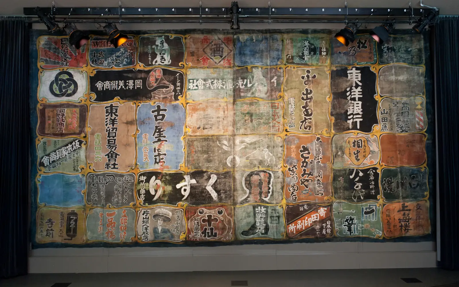 theatre curtain painted with Japanese characters advertising local businesses